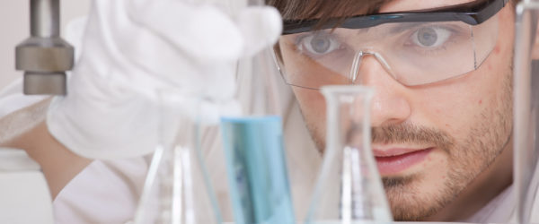 Male,Scientist,In,Research,Lab,Holding,Glass,Flask,With,Blue